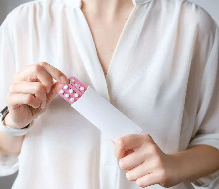 A woman holding a pack of oral contraceptive pills.